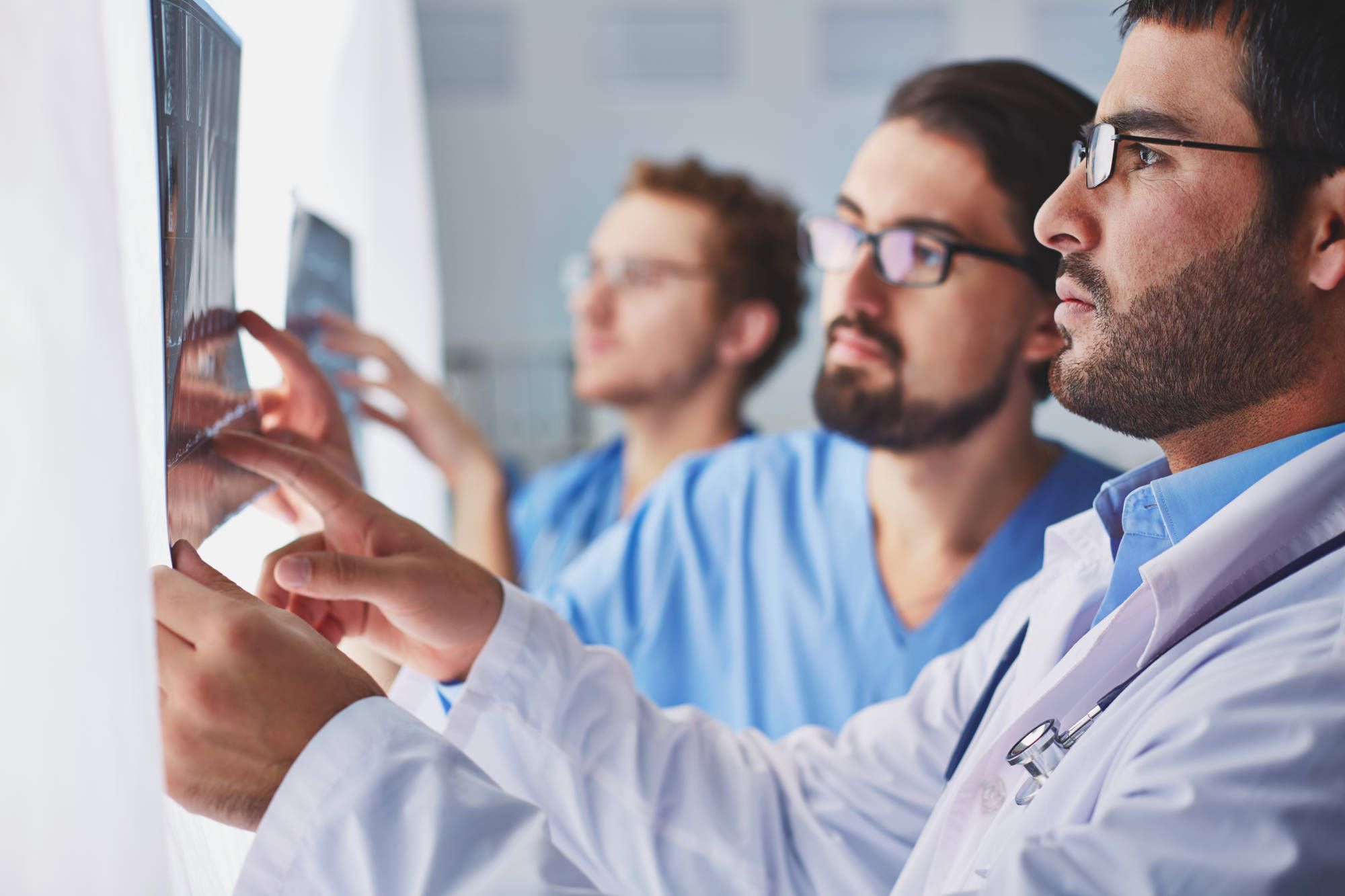 Tres médicos revisan imágenes diagnósticas
